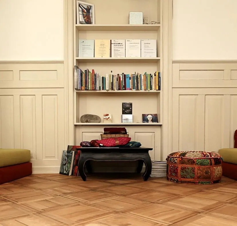 Cozy studio lounge area featuring a built-in bookshelf with certificates, floor seating, and low wooden table.