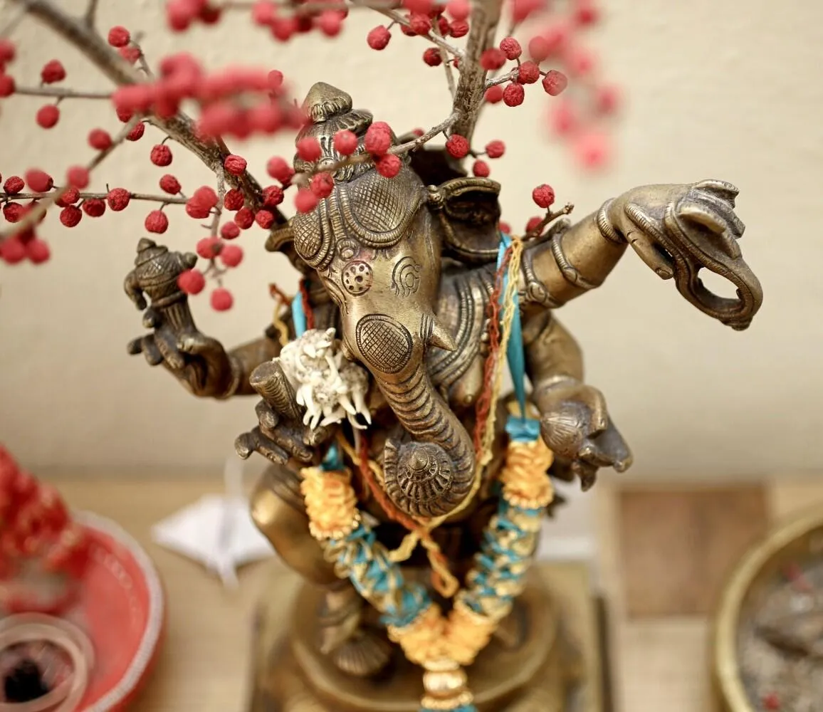 Bronze Ganesha statue decorated with garlands and red berries