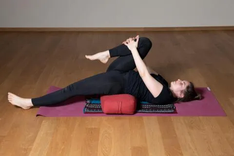Reclined leg stretch on bolster