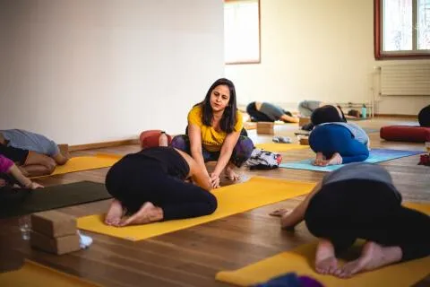 Yoga teacher guiding students in child's pose