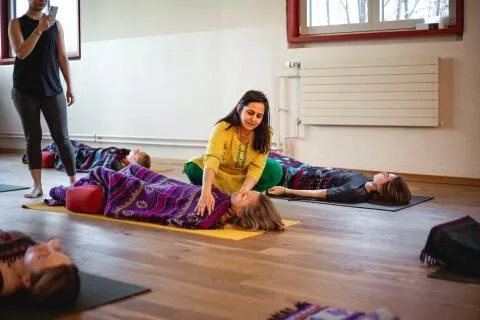 Yoga teacher adjusting a student in Savasana.